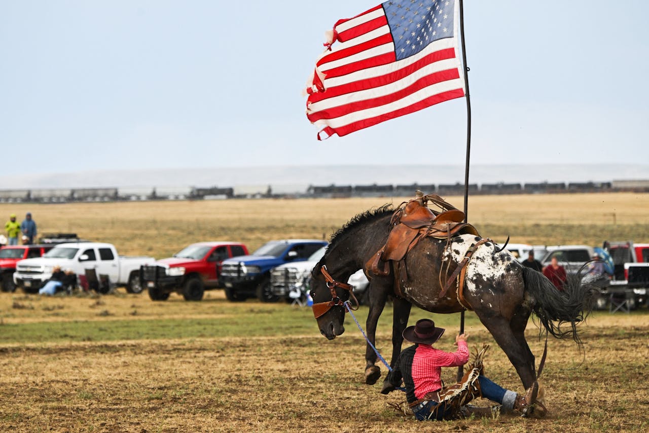 Tom Horn Days Cowboy Rendezvous rodeo in Bosler, Wyoming. De rodeorijder bijt in het stof na van het paard te zijn geworpen, maar zal het er niet bij laten zitten. Cowboy is onverminderd een lifestyle voor Amerikanen.
