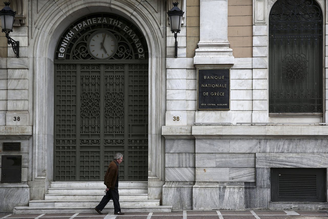 Een man loopt langs een kantoor van de National Bank of Greece.