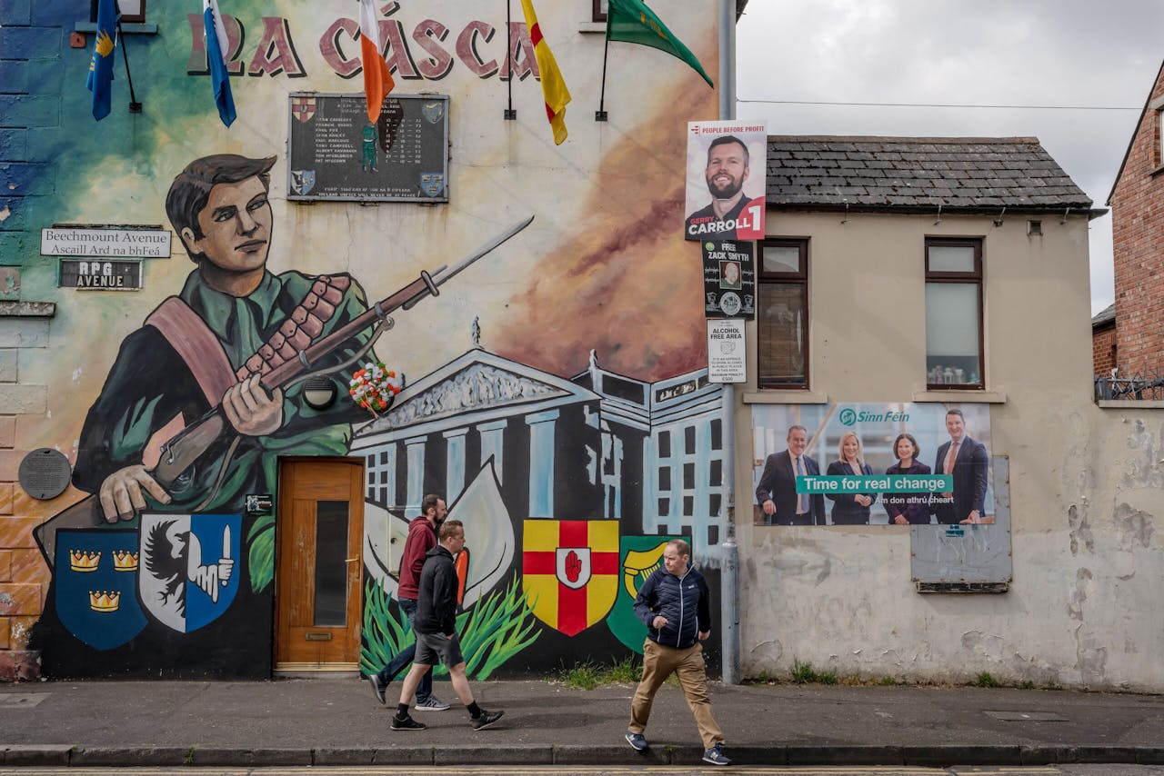 Verkiezingsposters op de Falls Road, een katholieke wijk in het westen van Belfast. De muurschildering verwijst naar de Paasopstand tegen het Britse gezag in Dublin, in 1916.