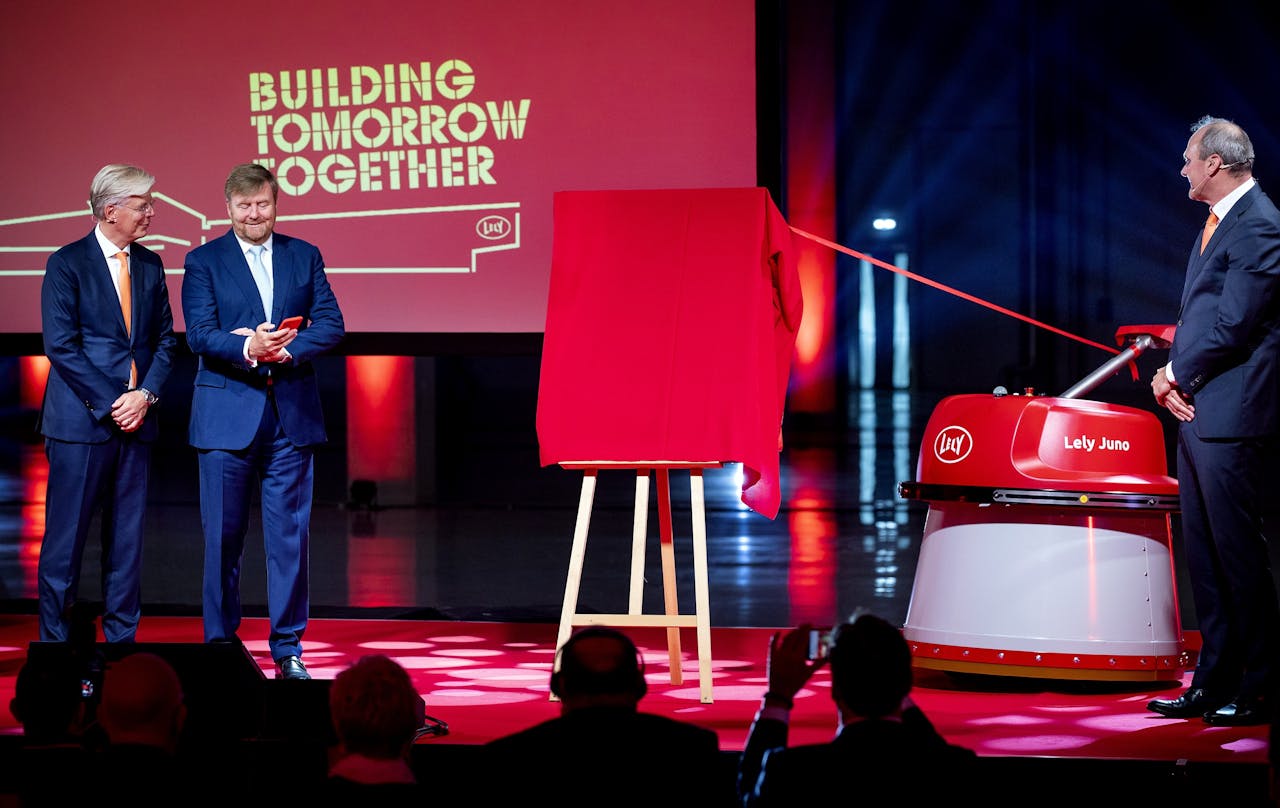 Koning Willem-Alexander was donderdag te gast bij melkrobotfabrikant Lely in Maassluis. Rechts op het podium staat de Lely Juno, een robot die geheel automatisch voer over een stalvloer naar vee kan schuiven.