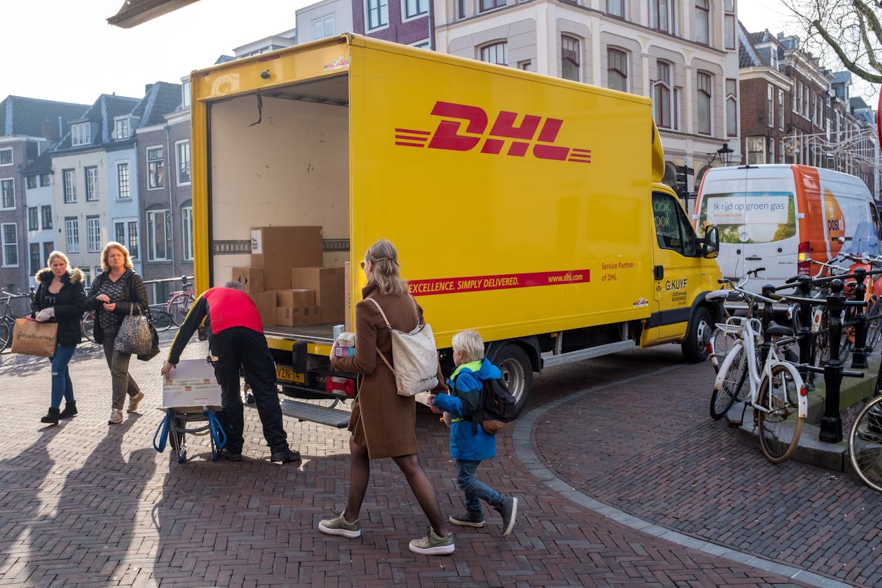 DHL-bus bezorgt pakjes in Amsterdam. De koerier gaat ook post bezorgen.