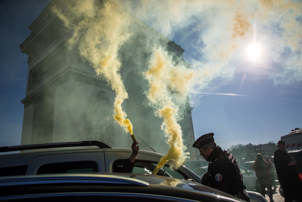 Een konvooi van Franse auto's, campers, trekkers en vrachtwagens brak zaterdag door politiebarricades heen en trok langs de Arc de Triomphe.