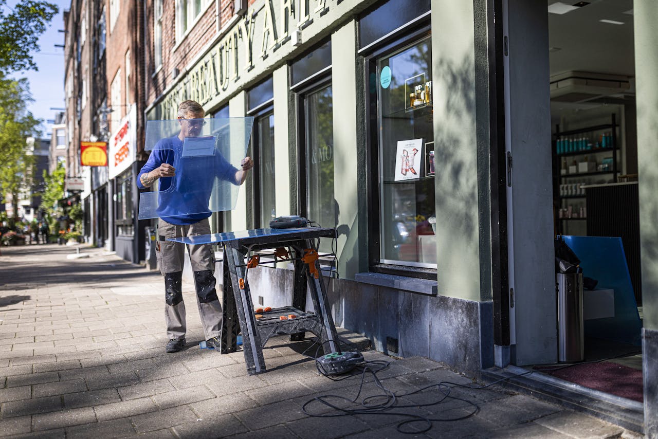 Bij een schoonheidssalon in Amsterdam wordt plexiglas gezaagd ter voorbereiding op de heropening maandag.