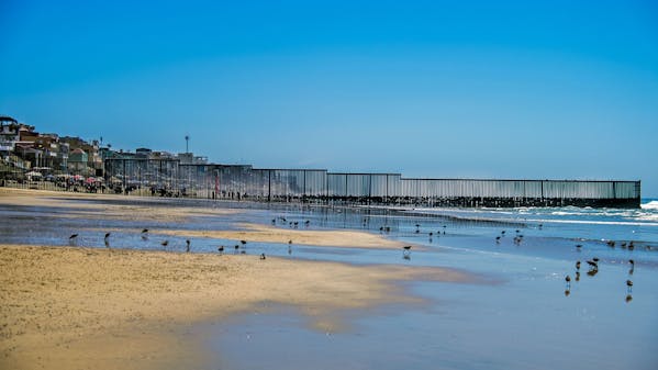 Een muur op de grens tussen de Verenigde staten en Mexico gezien vanaf de Amerikaanse kant. De muur gaat een stuk de Pacific in. - De muur staat tussen de Amerikaanse stad San Diego en de Mexicaanse stad Tijuana. Foto: Frank de Roo